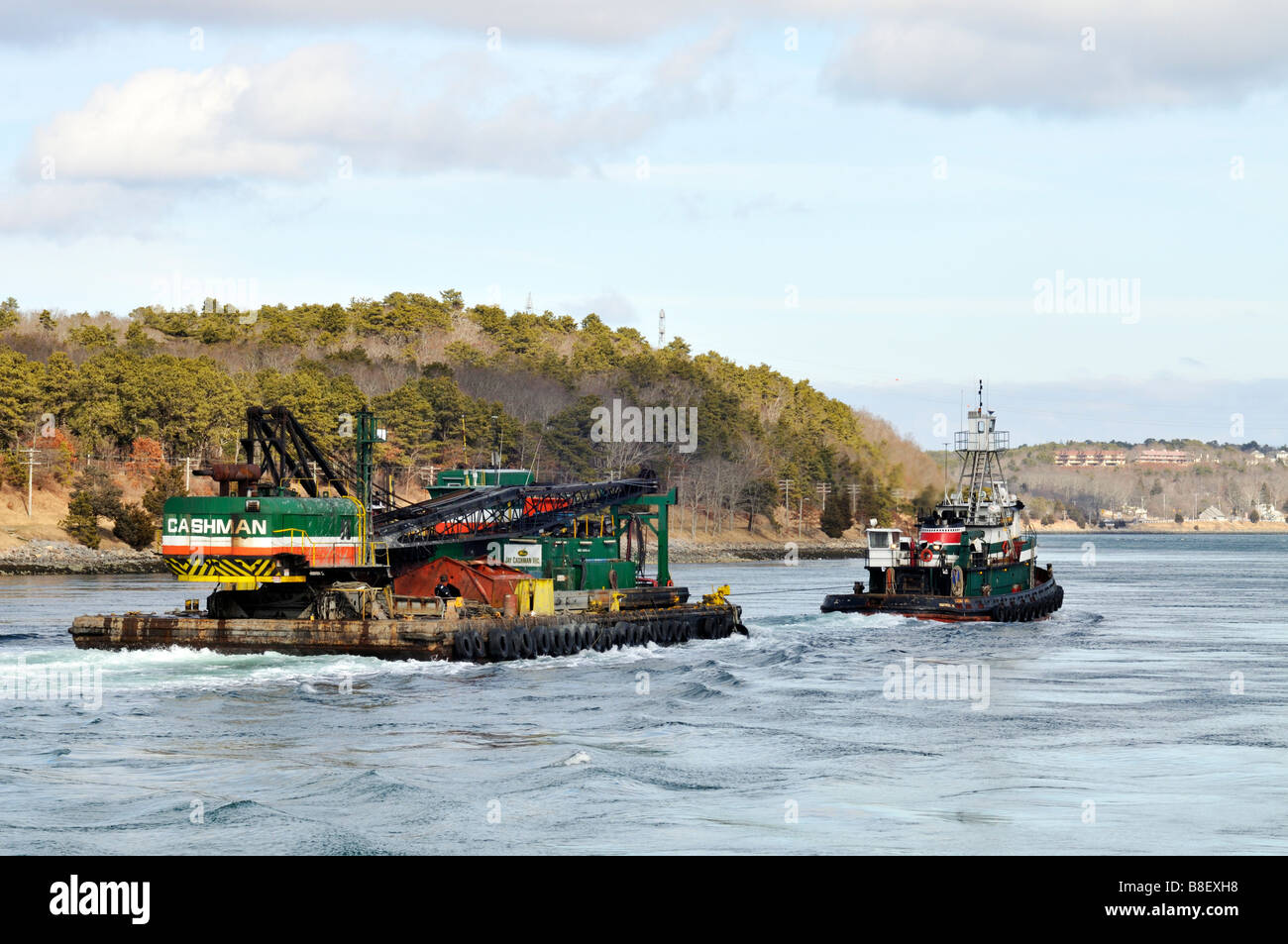 Tugboat towing a barge with crane and heavy equipment from Cashman Company through the Cape Cod Canal Stock Photo