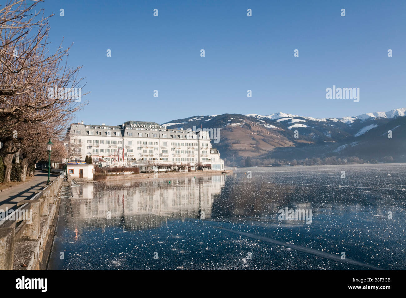 Frozen Zeller See lake and lakeside Grand Hotel in alpine resort in winter. Zell am See Austria Europe Stock Photo