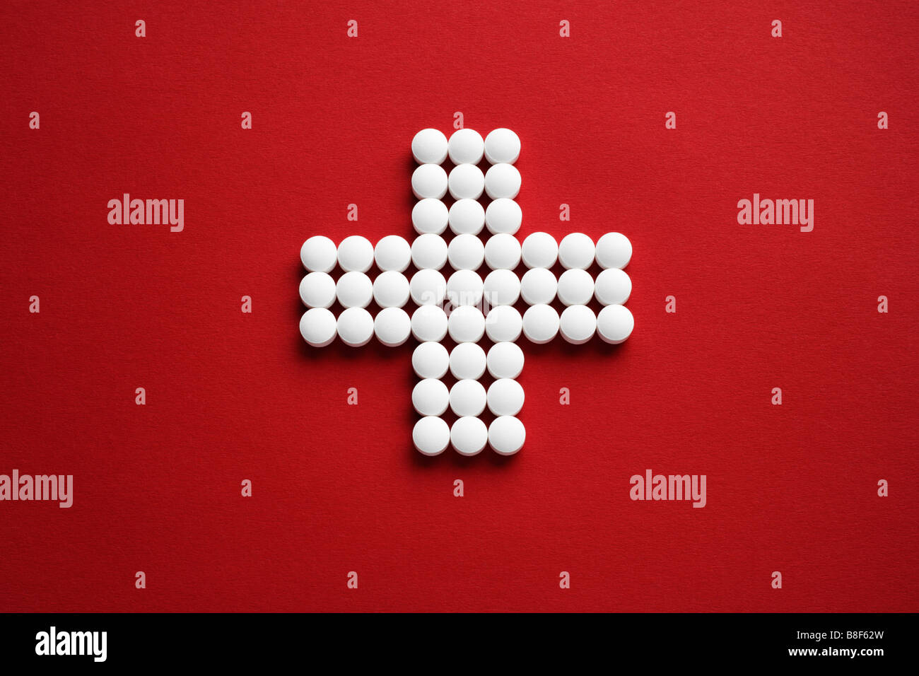 Tabletten als Kreuz gelegt auf roten Untergrund Stock Photo