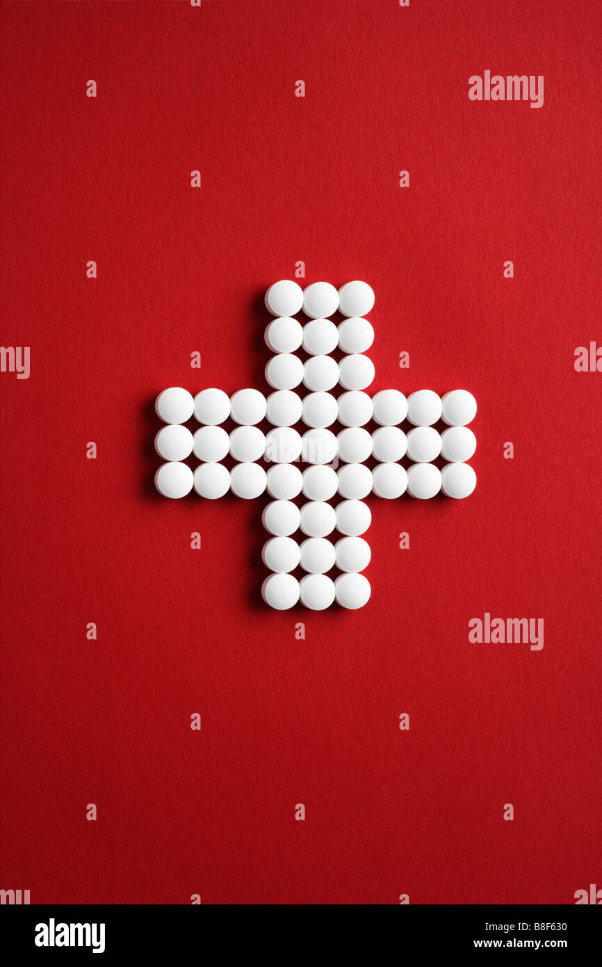 Tabletten als Kreuz gelegt auf roten Untergrund Stock Photo
