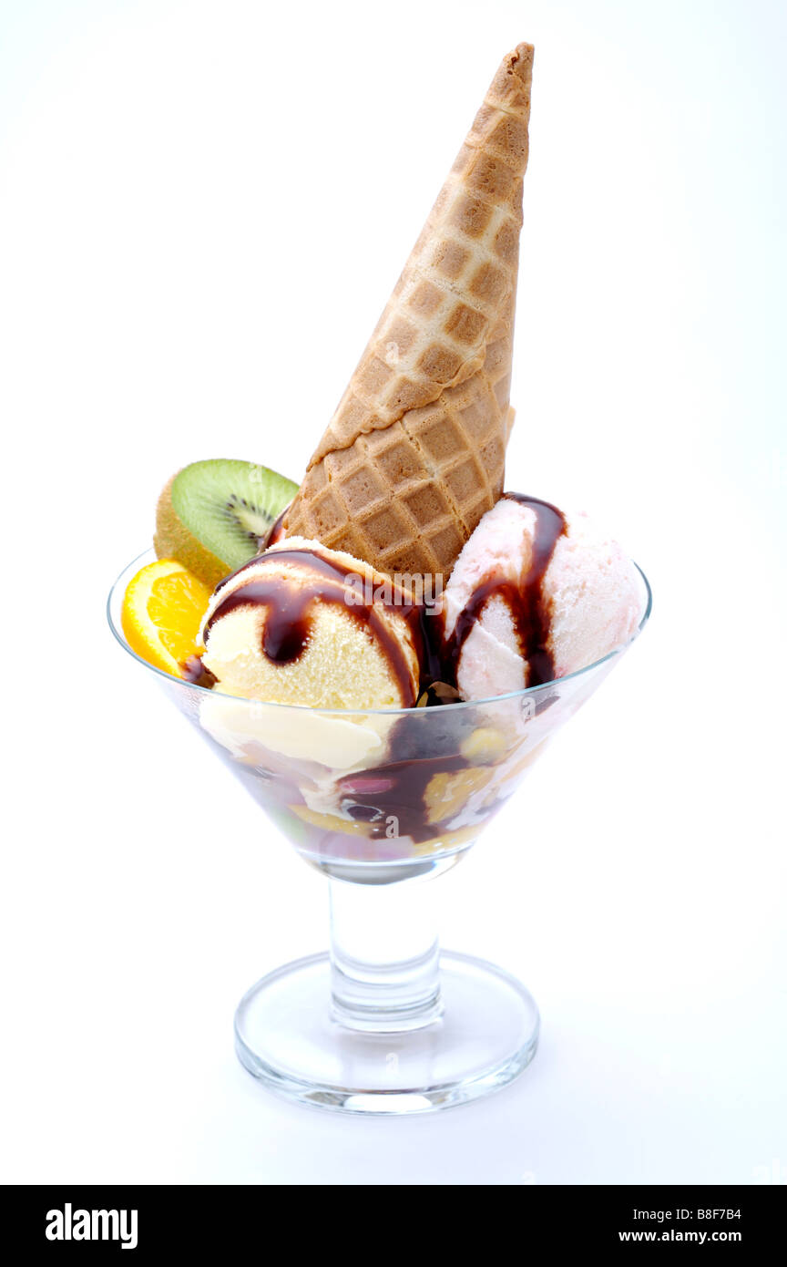 Two scoops of ice cream and an ice cream cone in a glass with fruit garnish Stock Photo