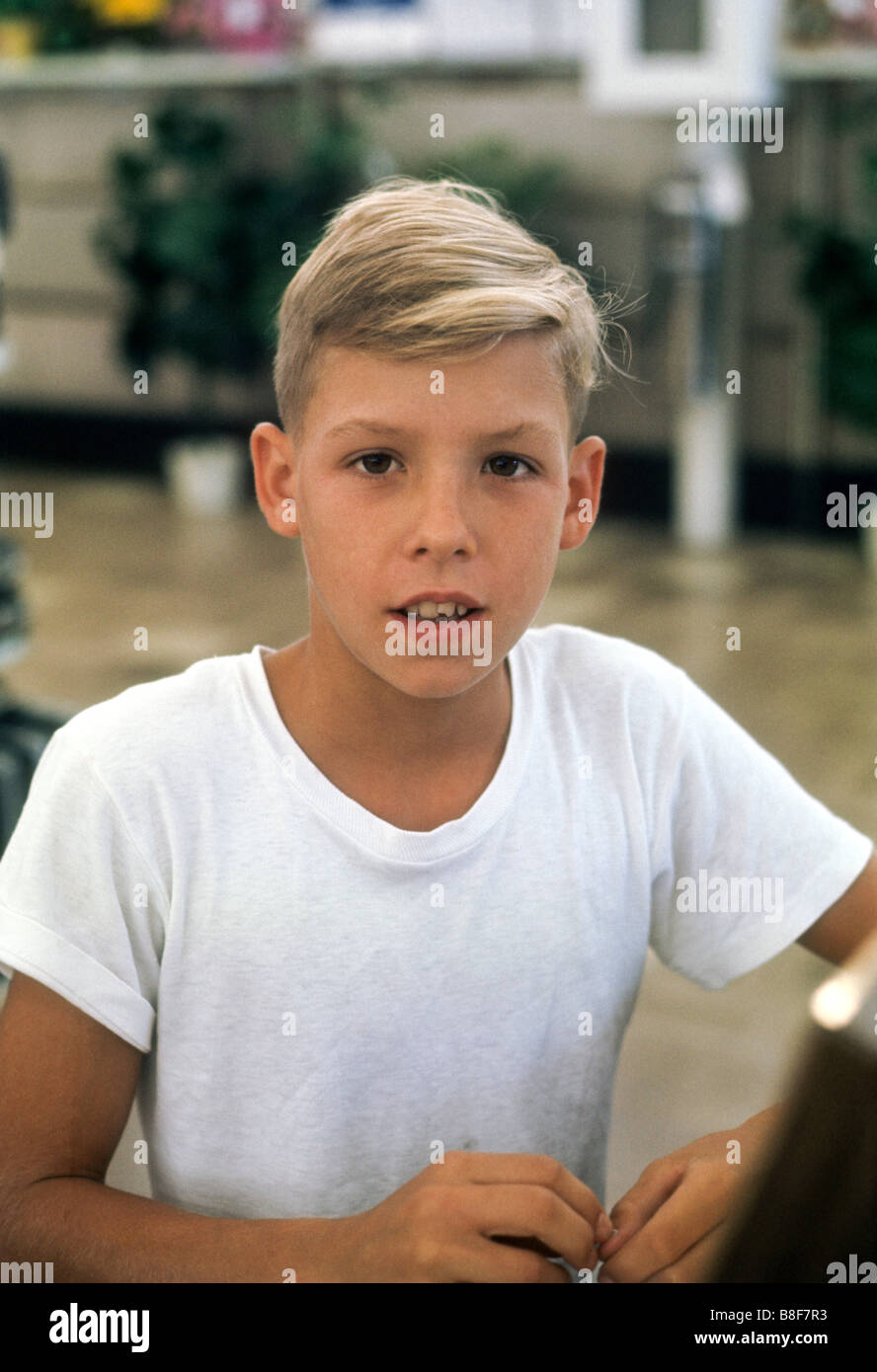 Blond boy in white T shirt looks intently at camera Stock Photo
