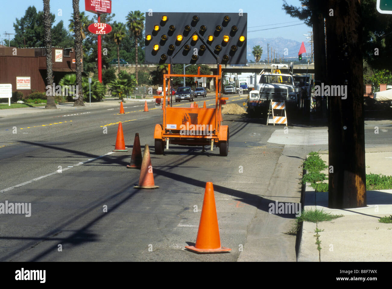 Highway sign with flashing arrow lights warns drivers of closed lane in