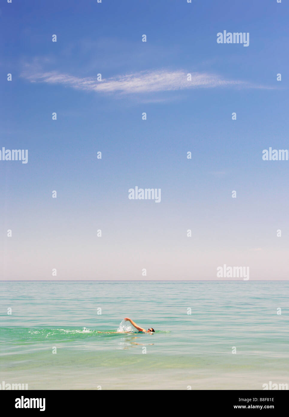 Young woman with sunglasses swimming backstroke in calm sea Stock Photo