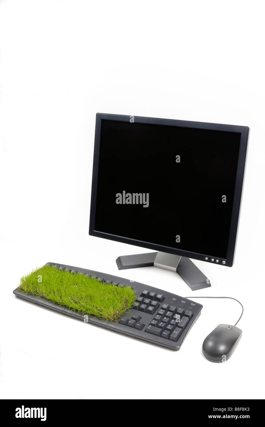 Desktop computer, mouse and keyboard with grass growing out of it. Stock Photo
