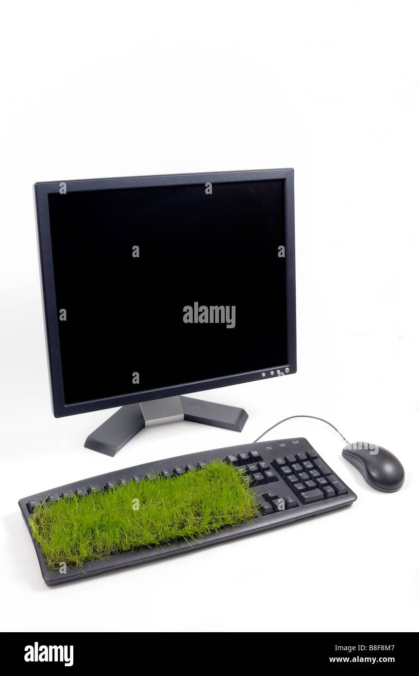 Desktop computer, mouse and keyboard with grass growing out of it. Stock Photo