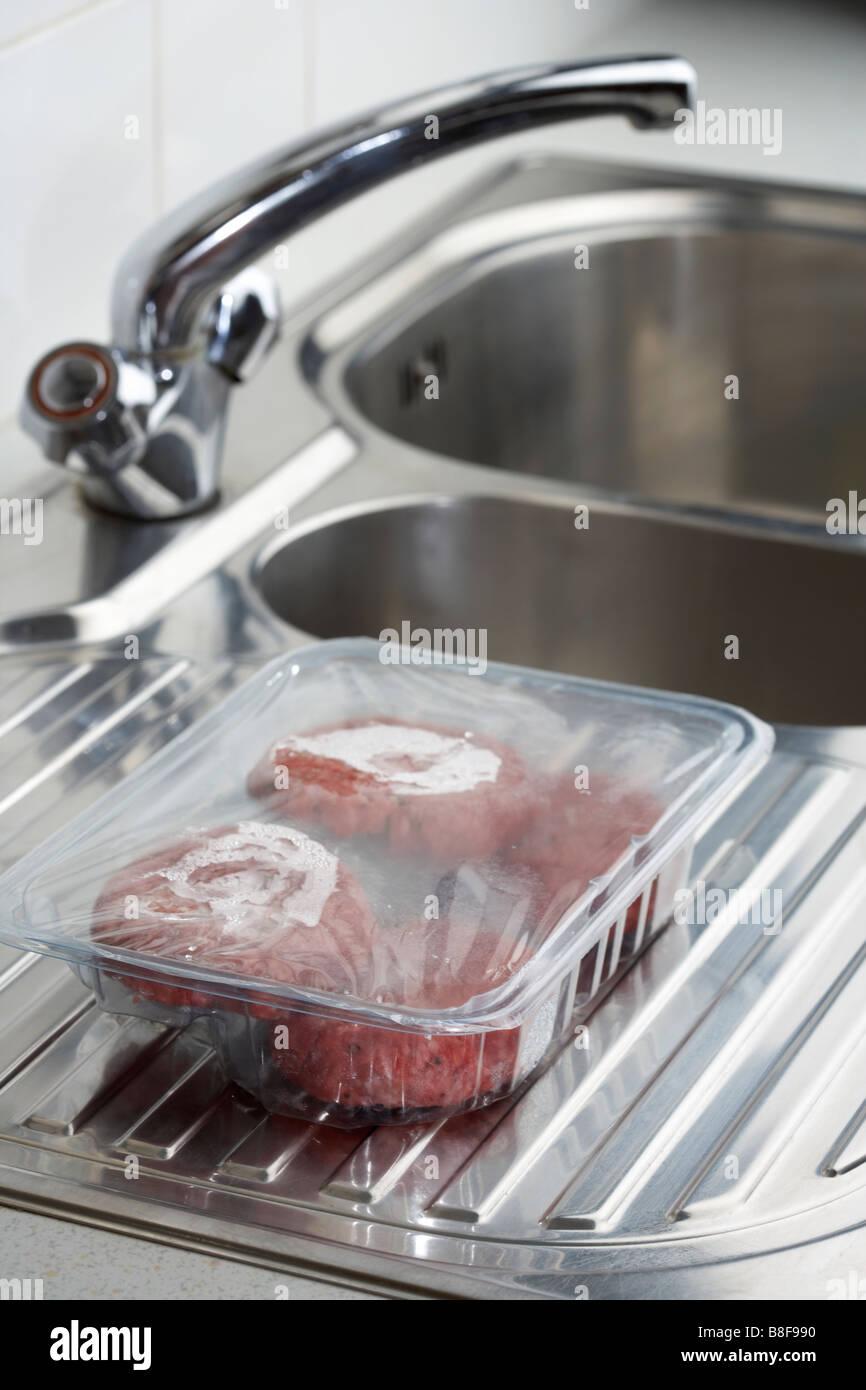 Four Beefburgers In A Plastic Tray Defrosting At Room