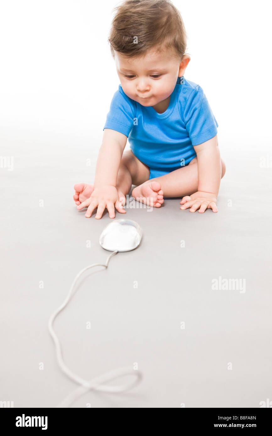 Baby on floor playing with computer mouse Stock Photo