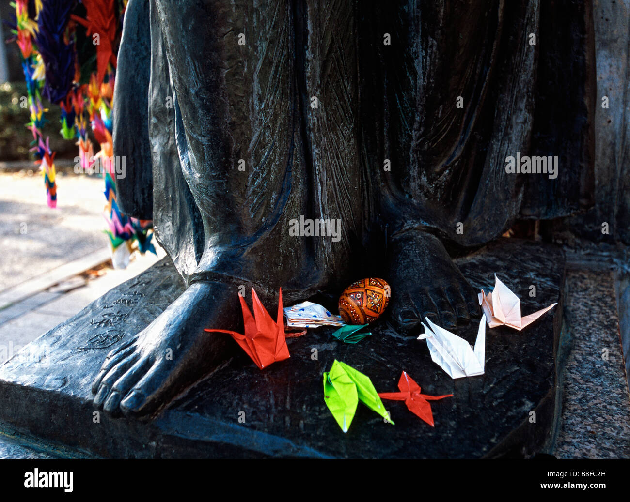 Paper cranes are laid at the feet of a statue in Hiroshima, Japan Stock Photo