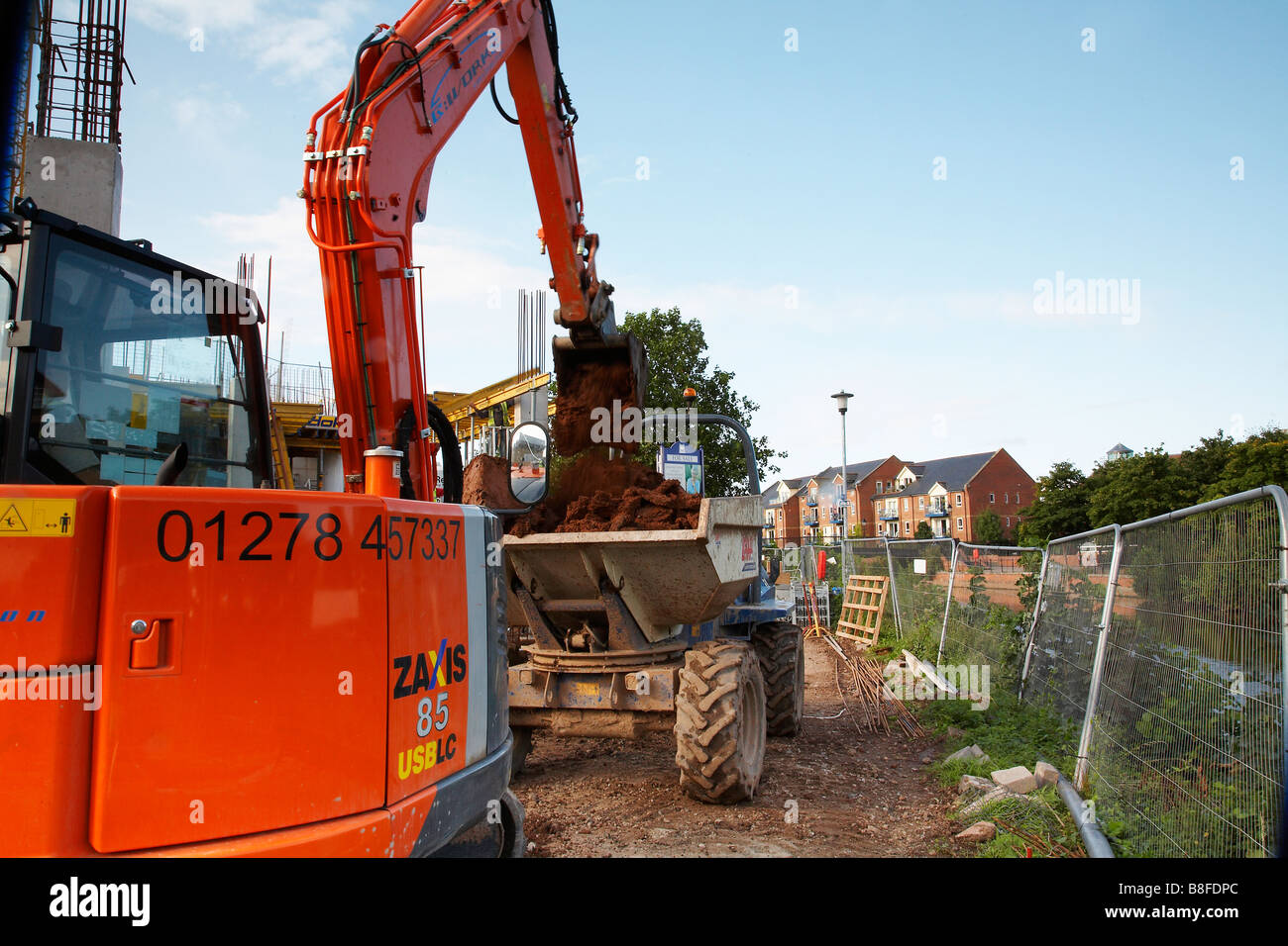 Construction of new apartments at taunton cricket club. Jcb loading a dump truck with earth Stock Photo