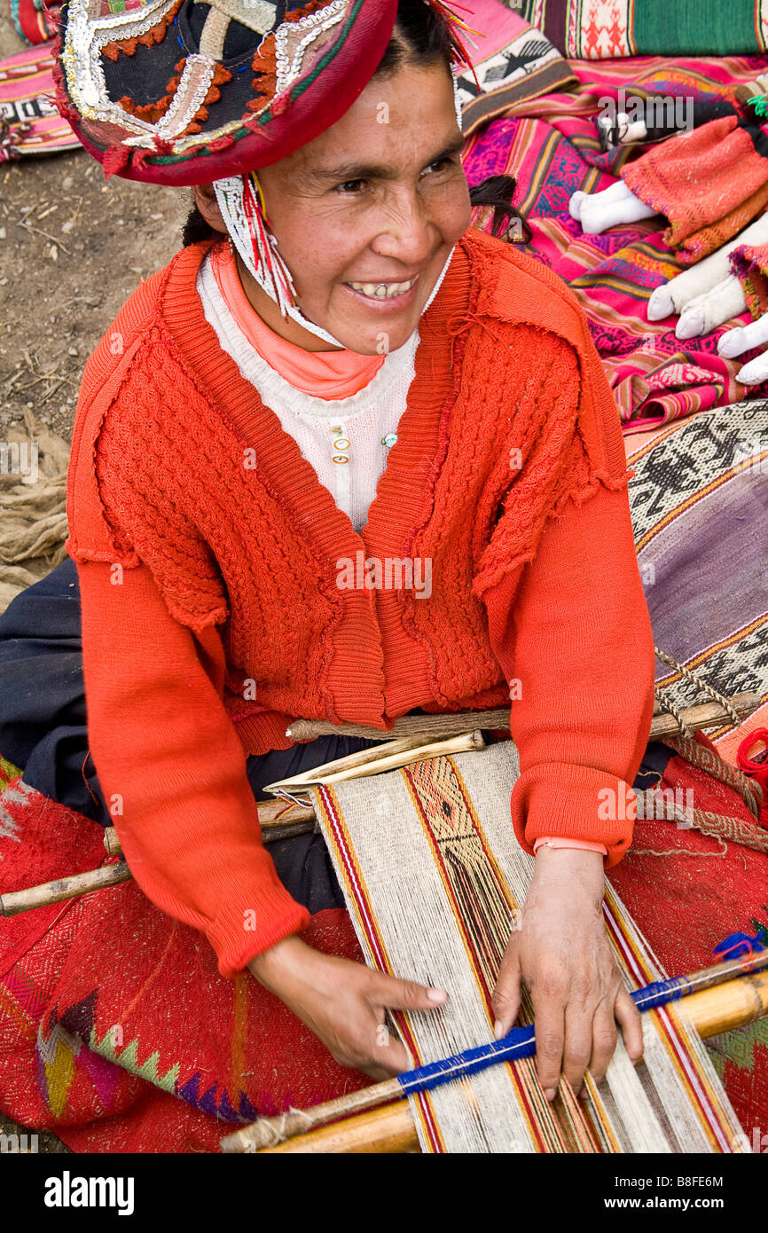 An Andean woman sits on the ground weaving alpaca wool into various products. Patacancha Valley, Peru. Stock Photo