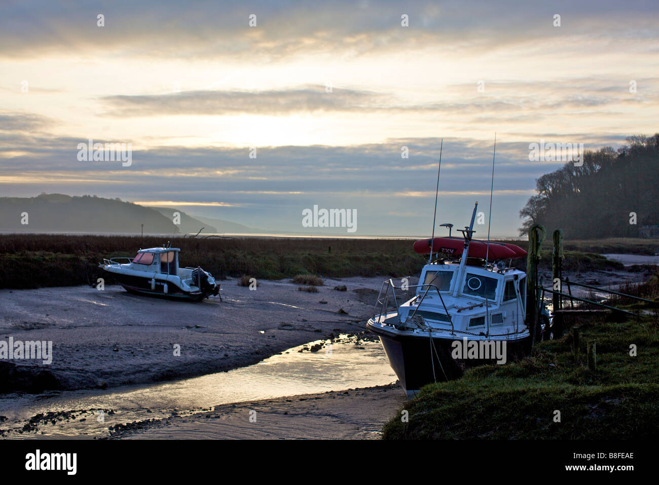 Fishing boats at sunrise on the Taf estuary at Laugharne in West Wales Stock Photo