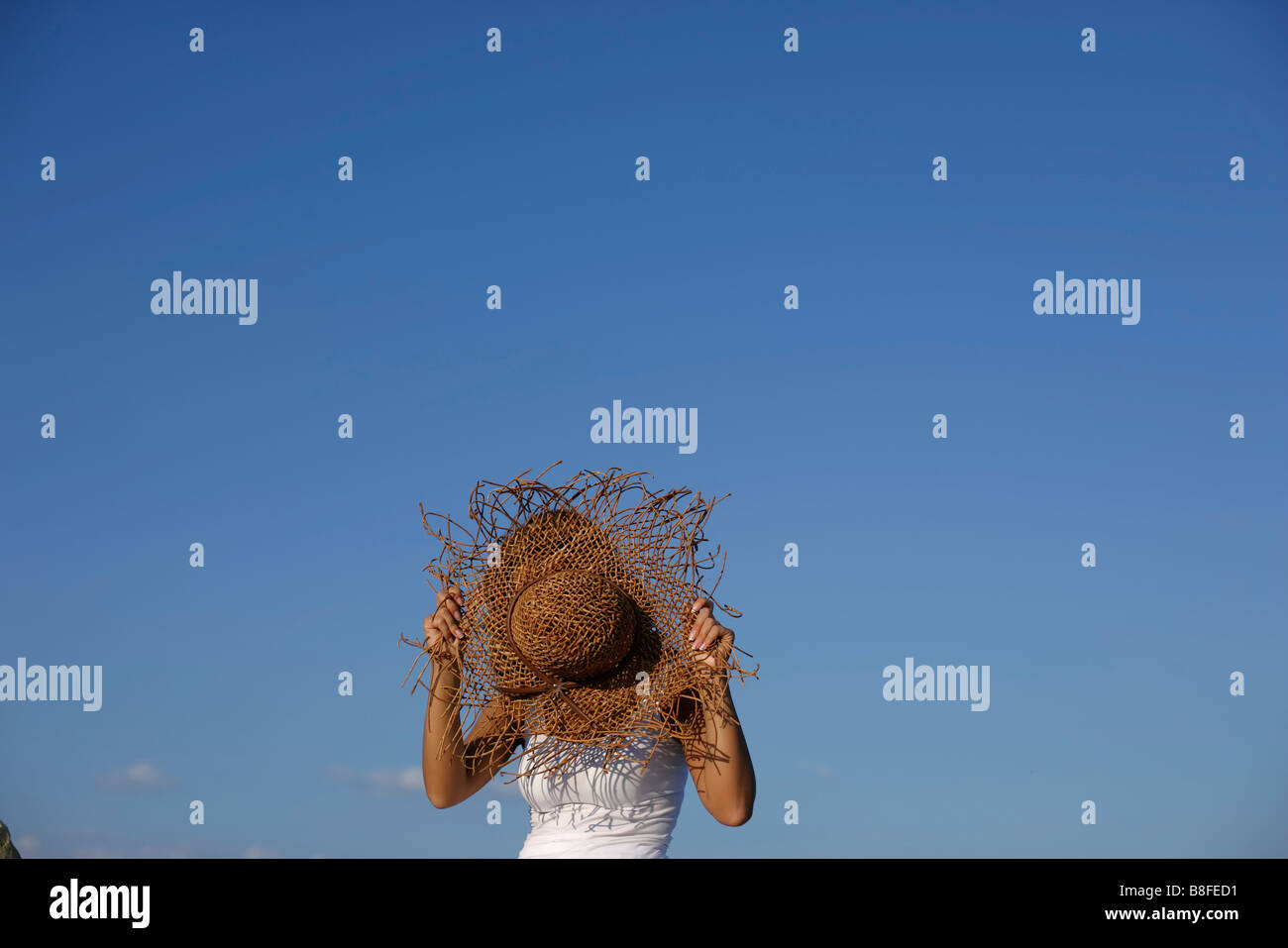 Woman covering her face by a straw hat Stock Photo - Alamy