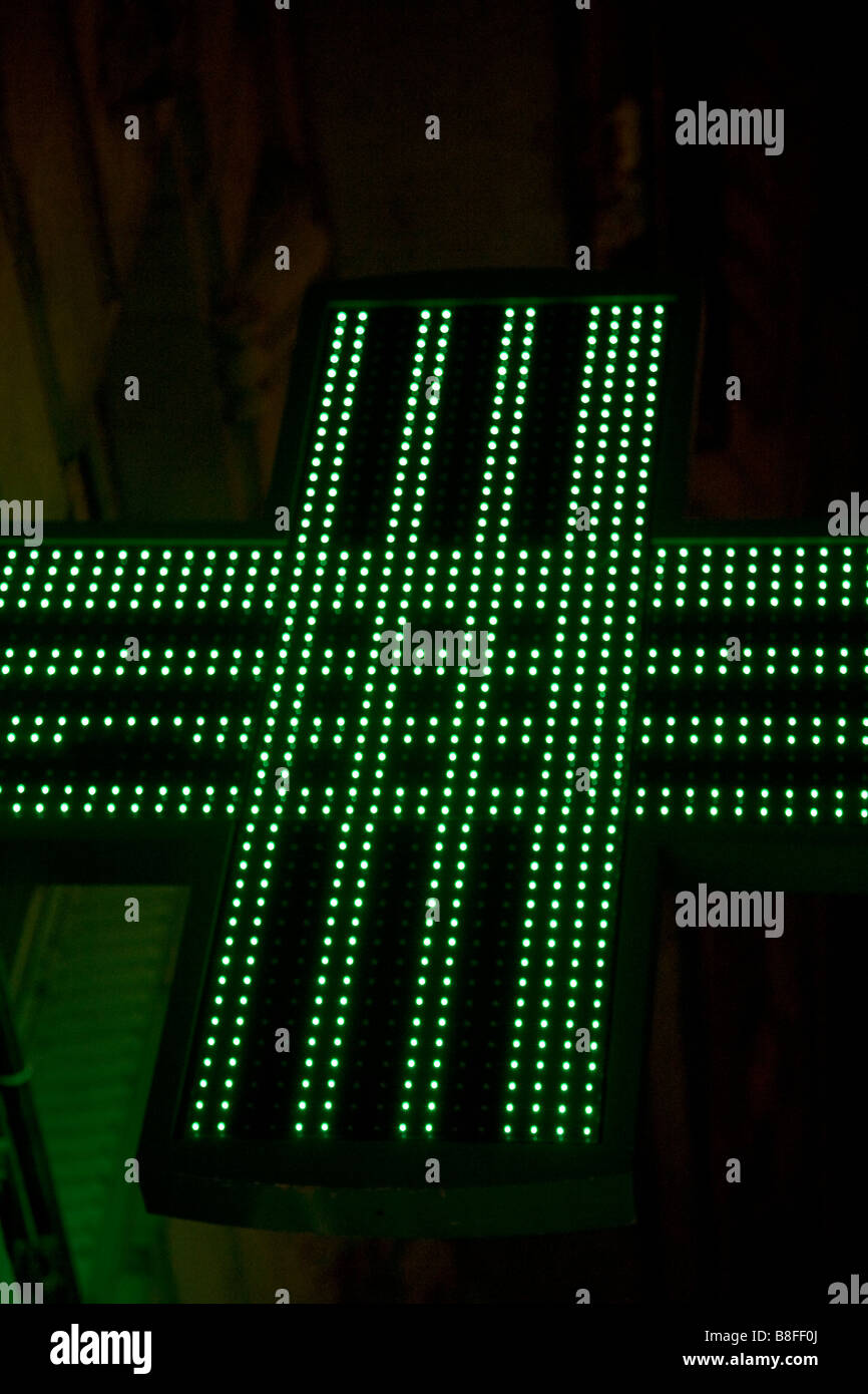 A typical scene in Paris, a neon sign advertising a pharmacy glows in the dark. Stock Photo