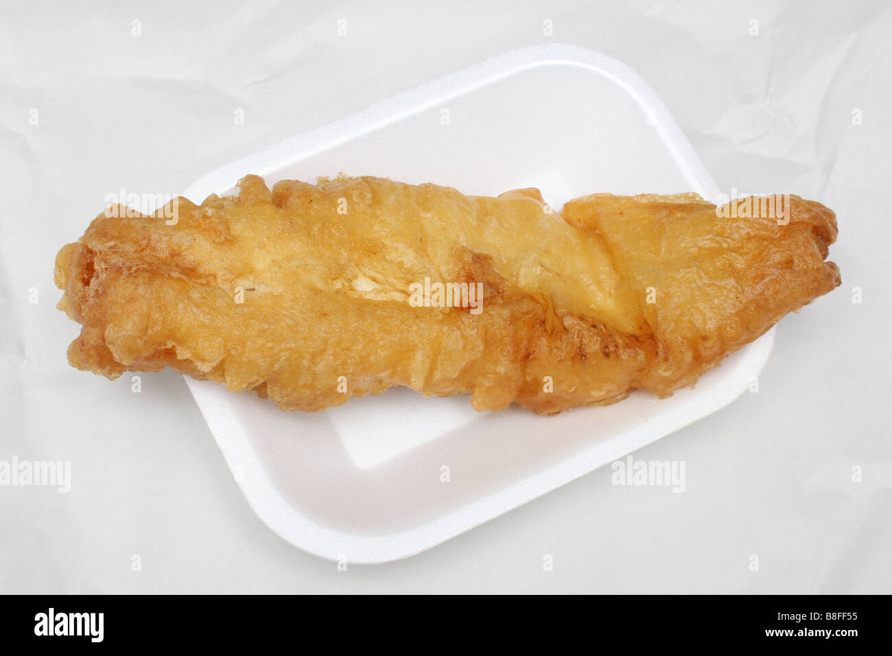 A piece of deep fried cod from a chip shop. Stock Photo