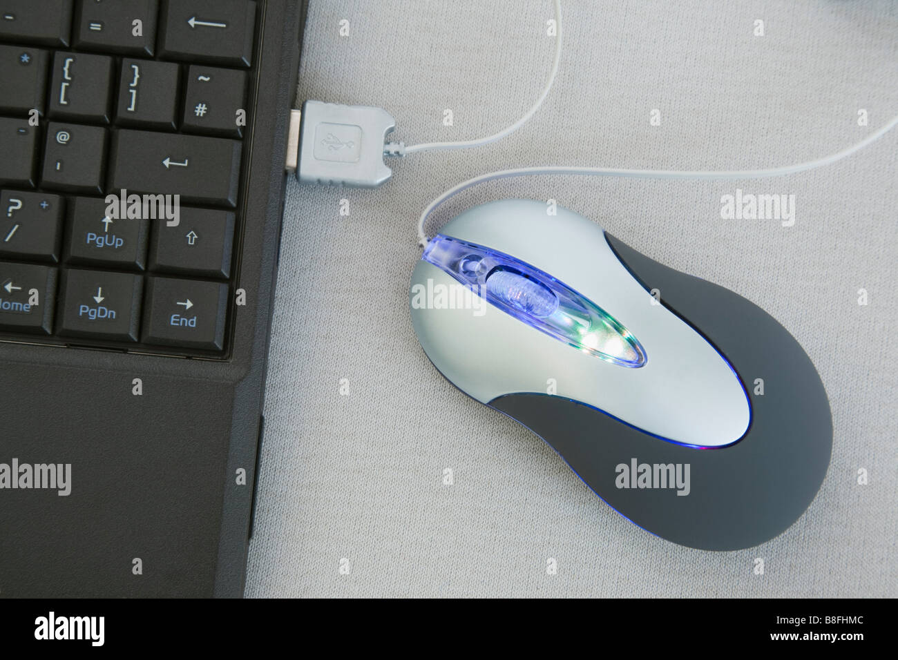 Studio Still Life Illuminated mouse connected to USB port on laptop computer Stock Photo