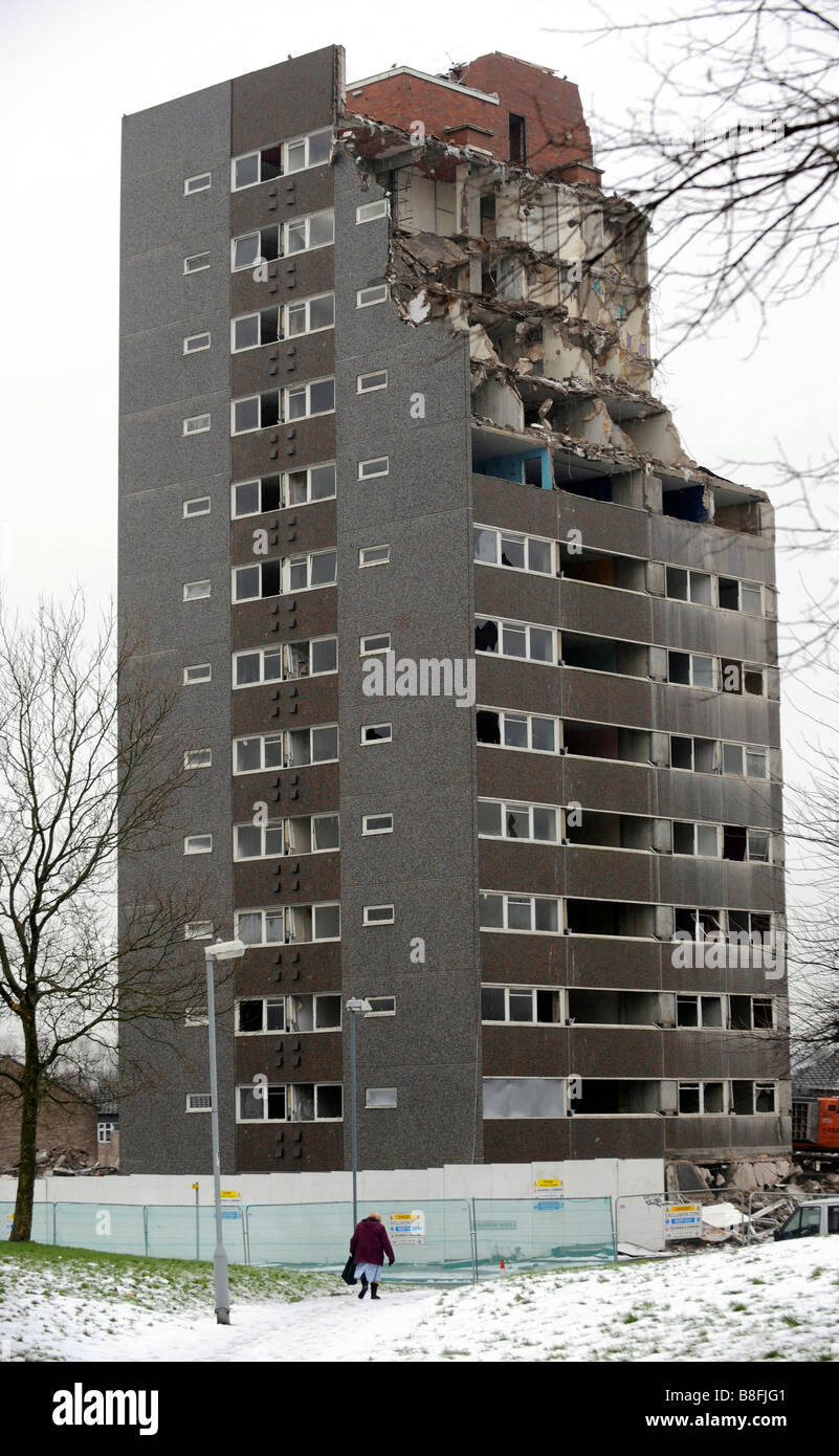 Demolition of 1960's high rise tower block of flats in the inner city area of Highgate, Birmingham. An elderly woman walks past. Stock Photo