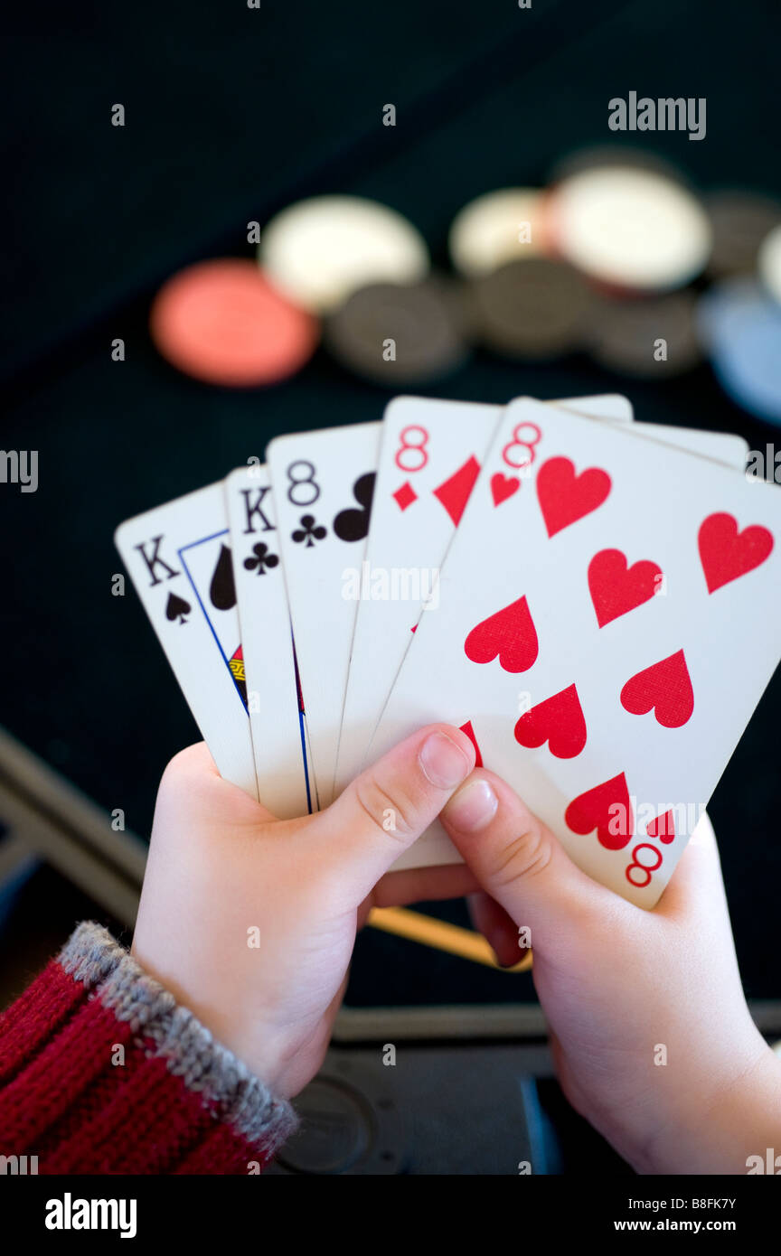 Young child holds a full house hand of poker Stock Photo