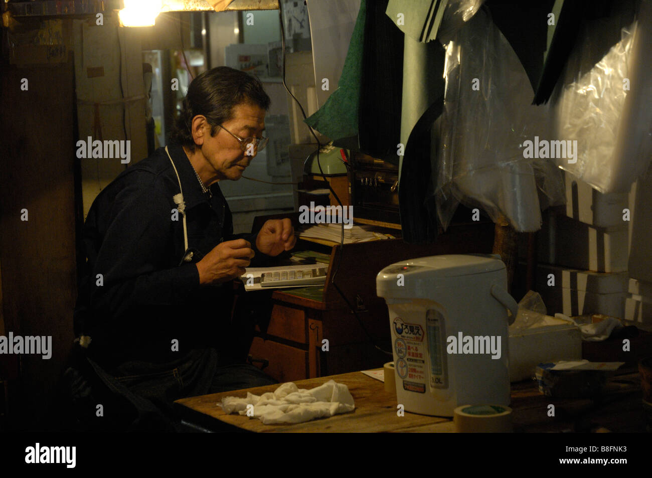 A seller at Tokyo's Tsukiji fish market checks his accounts after trading Stock Photo
