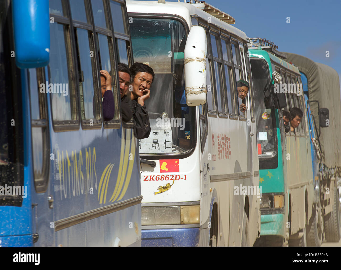 Bus passengers stuck in traffic looking out of the windows of the coaches. Tibet, China Stock Photo