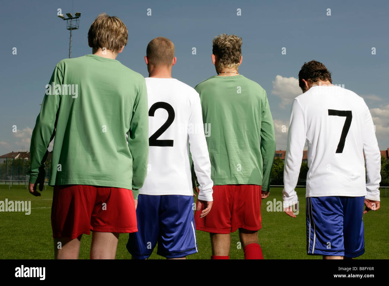 Four footballers of adverse teams standing next to each other, rear view Stock Photo