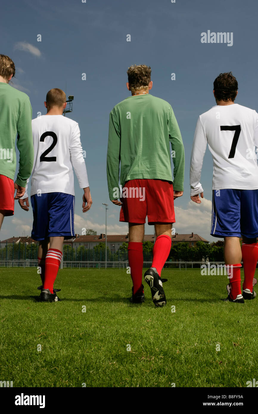 Four footballers of adverse teams standing next to each other, rear view Stock Photo