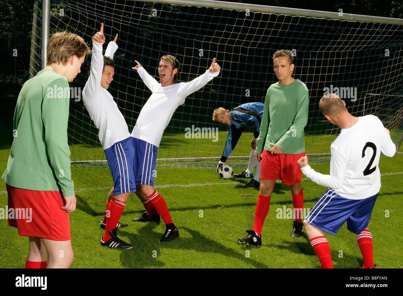 Three young footballers are happy about having won a game whereas the ...