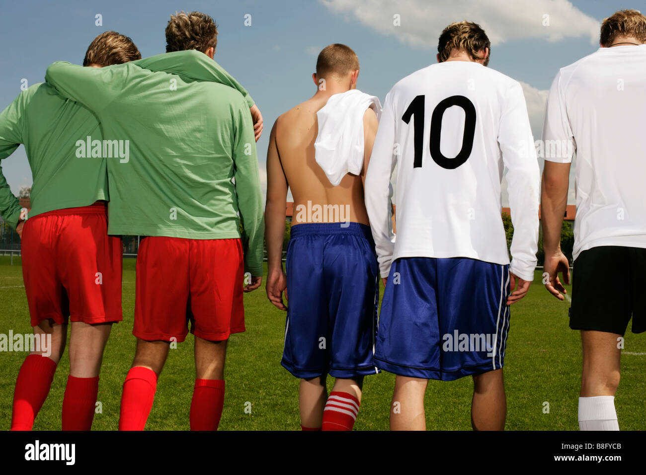 Five footballers of adverse teams walking next to each other, rear view Stock Photo
