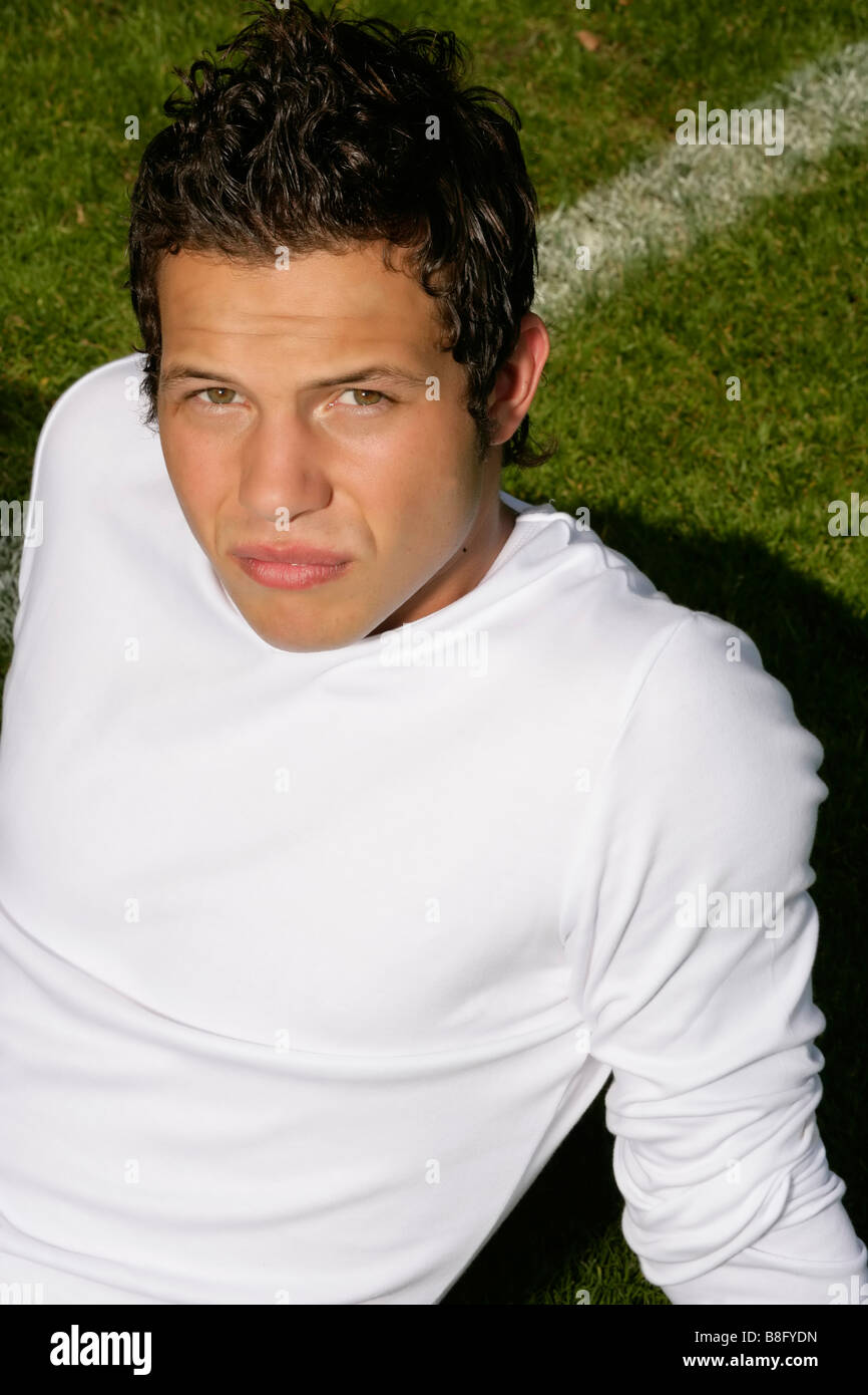 Young man with brown hair sitting on a pitch, closeup Stock Photo Alamy