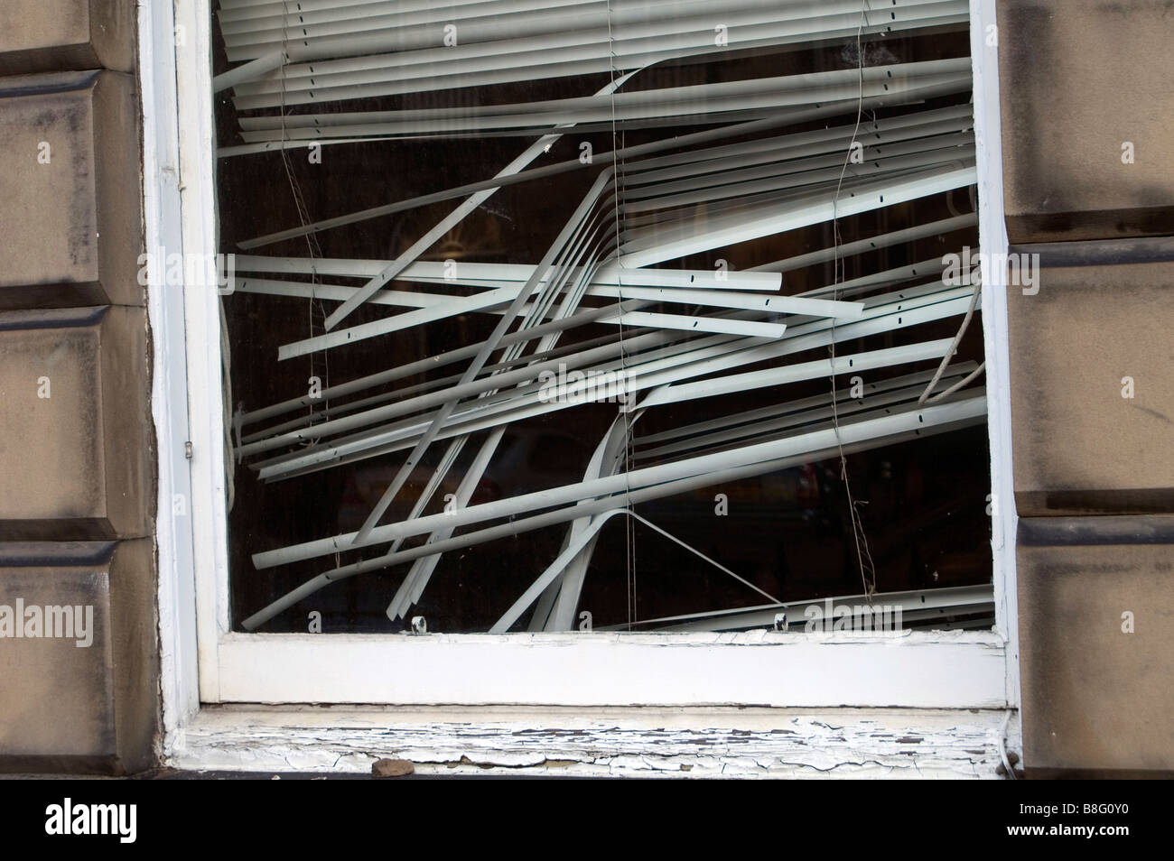 Broken blind in the window of a deserted office Stock Photo