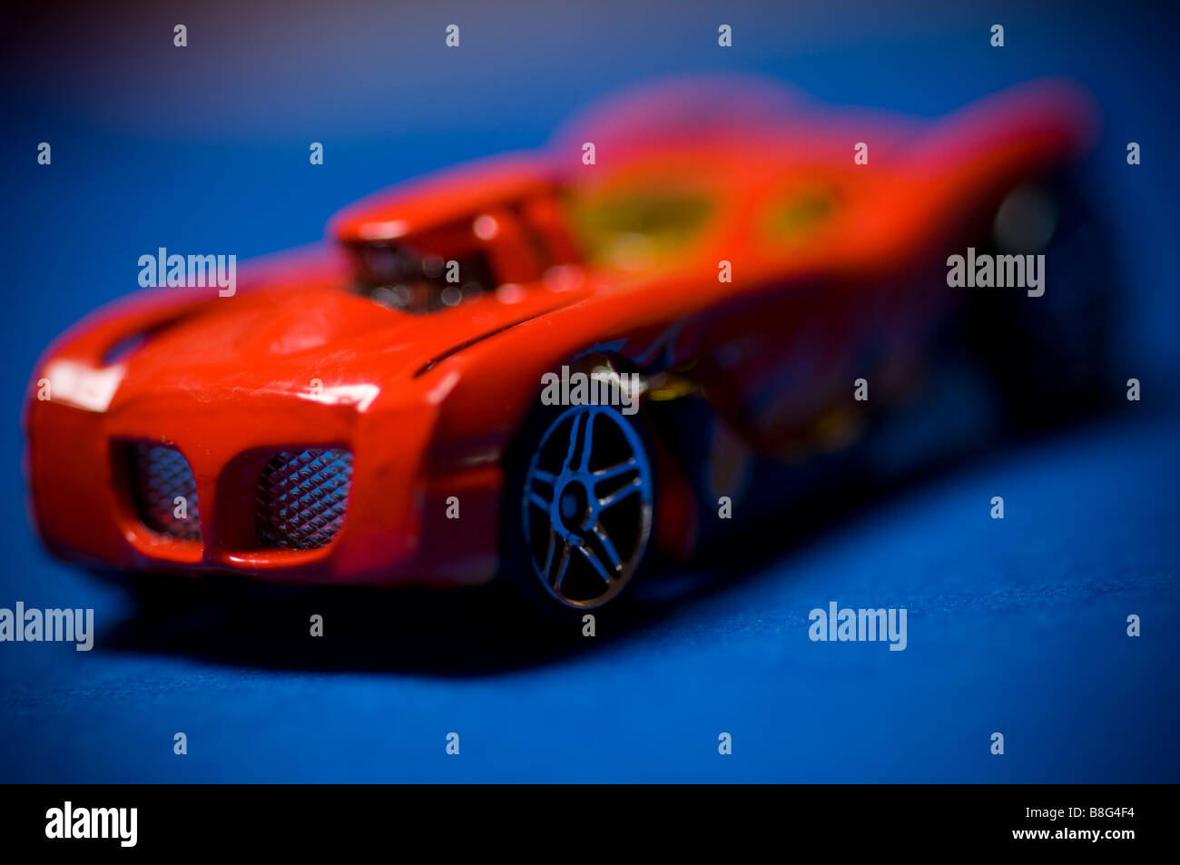 A red toy sports car against a blue background. Stock Photo