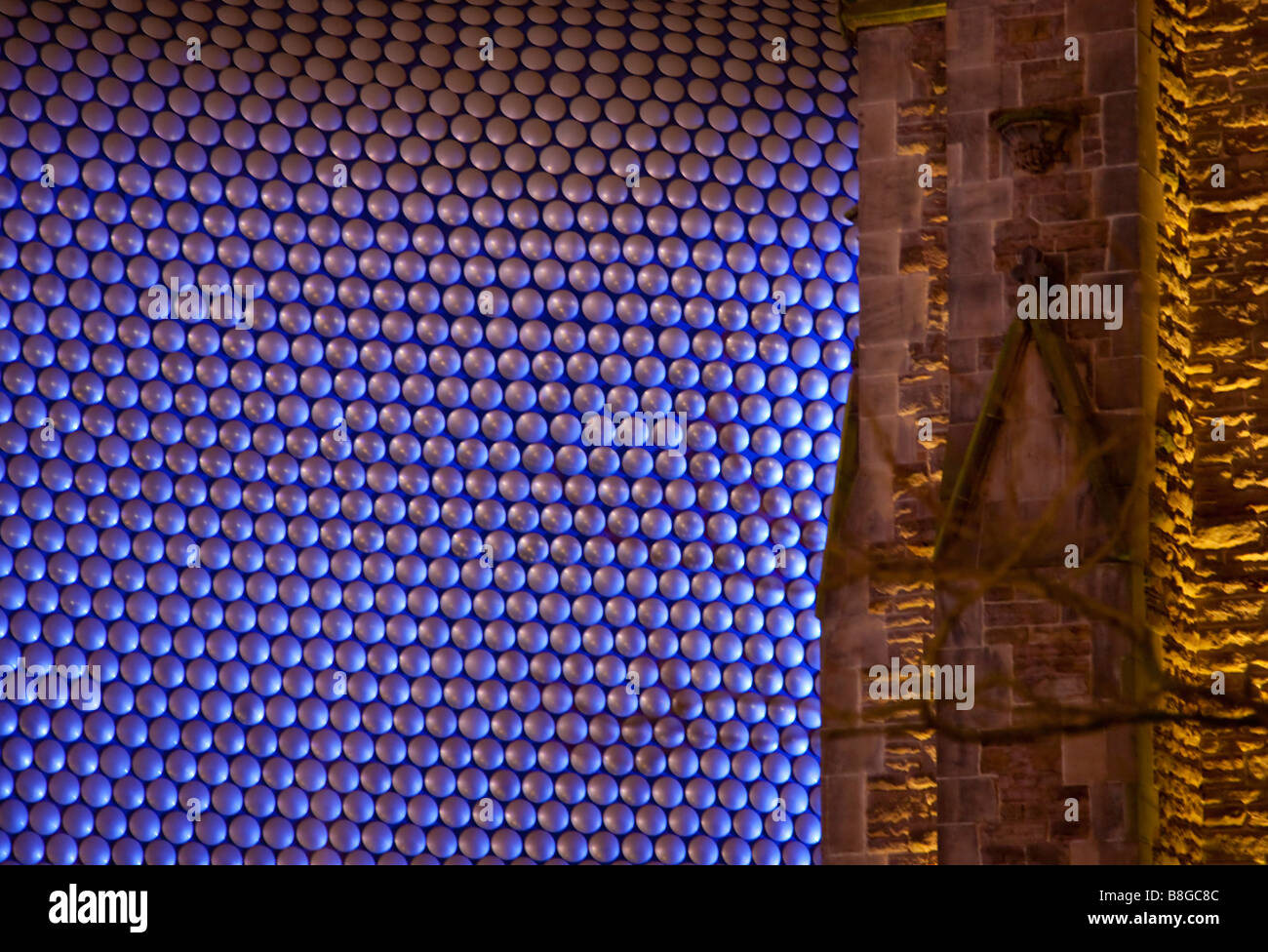 The architecture of Selfridges department store contrasts with St Martins church Birmingham England at night Stock Photo