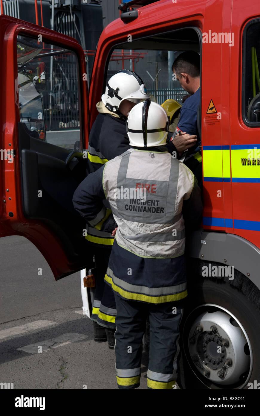 Fire Incident Commander consults with colleagues whilst passing informative message over radio at incident Stock Photo