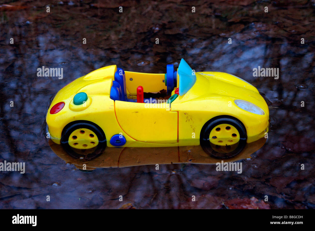 a toy sports car  in a puddle of water. Stock Photo