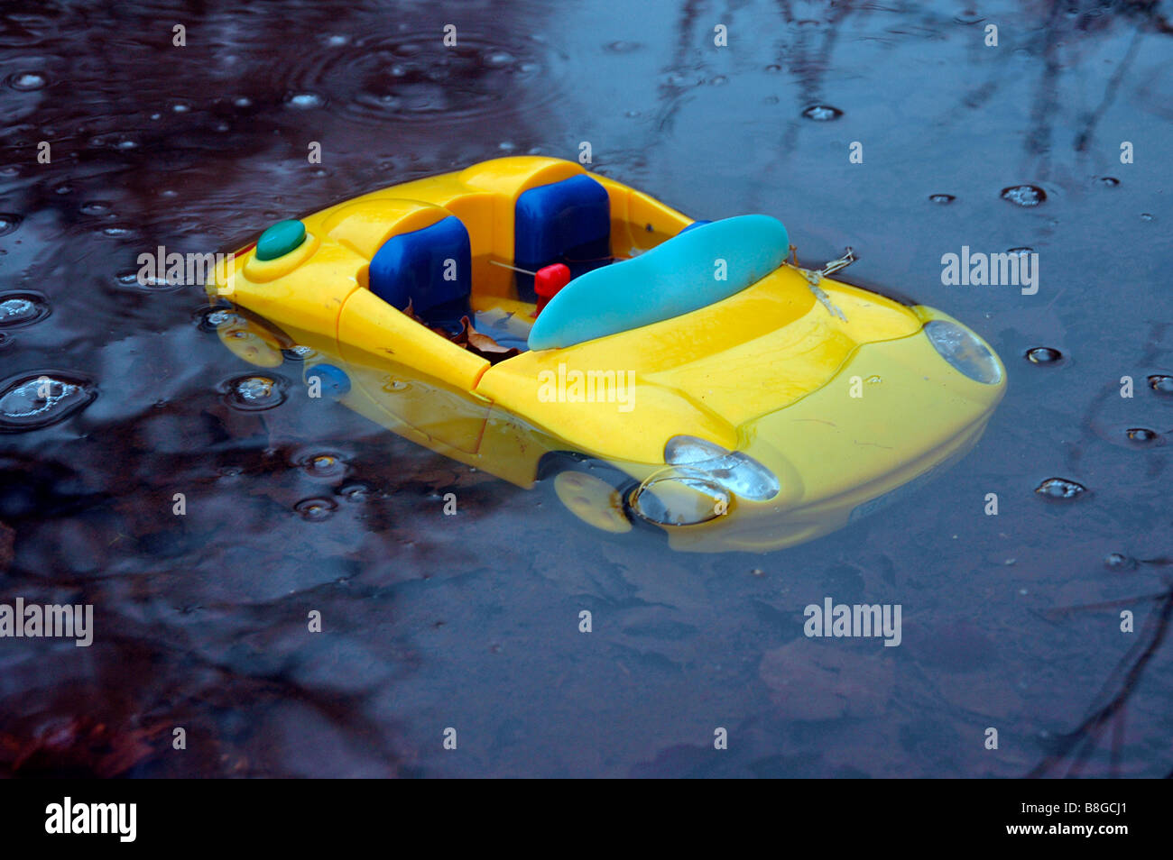 a toy sports car sinking in a puddle of water. Stock Photo