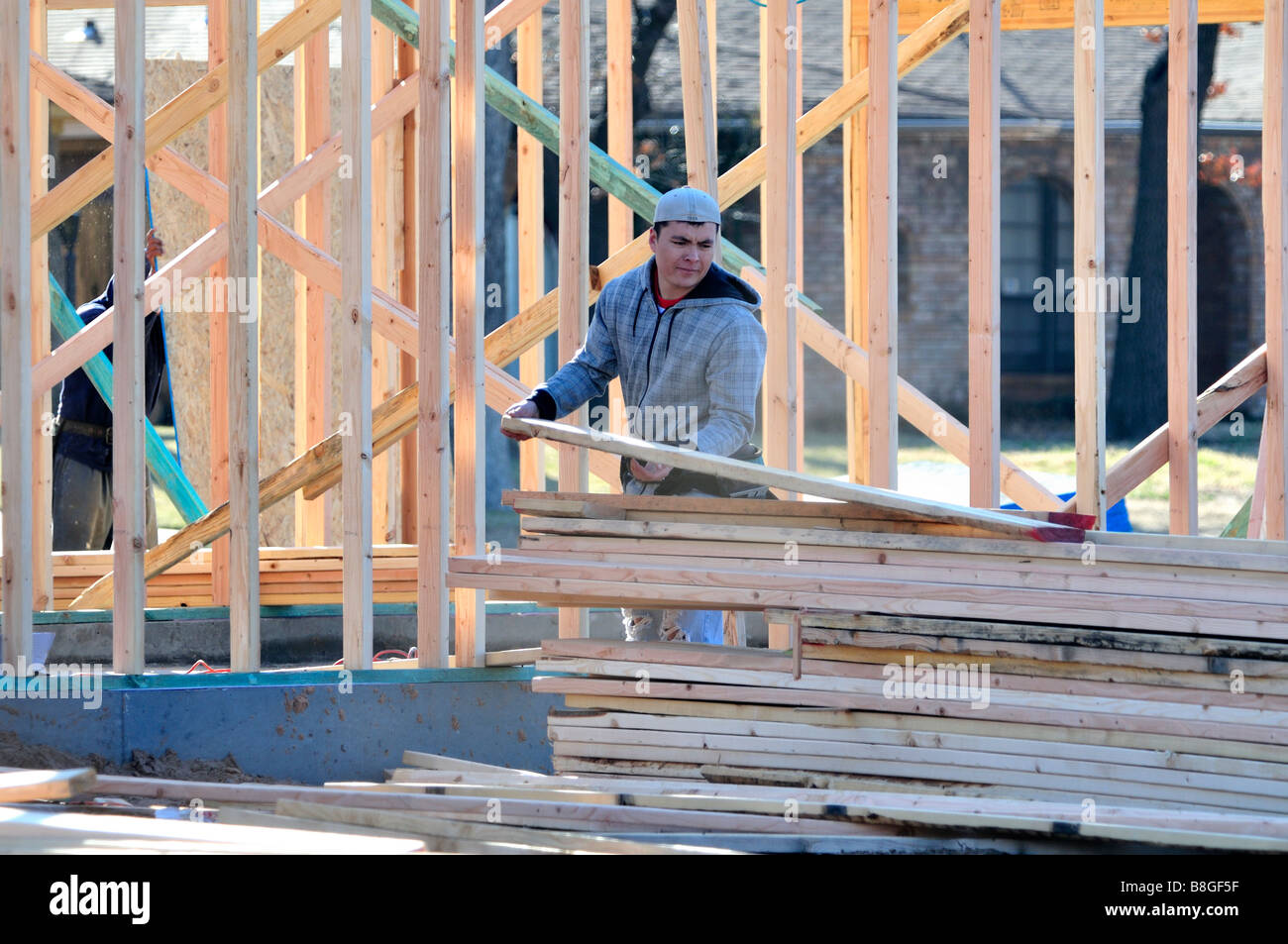 A workman picks up a board for a new home construction. Oklahoma City, Oklahoma, USA Stock Photo