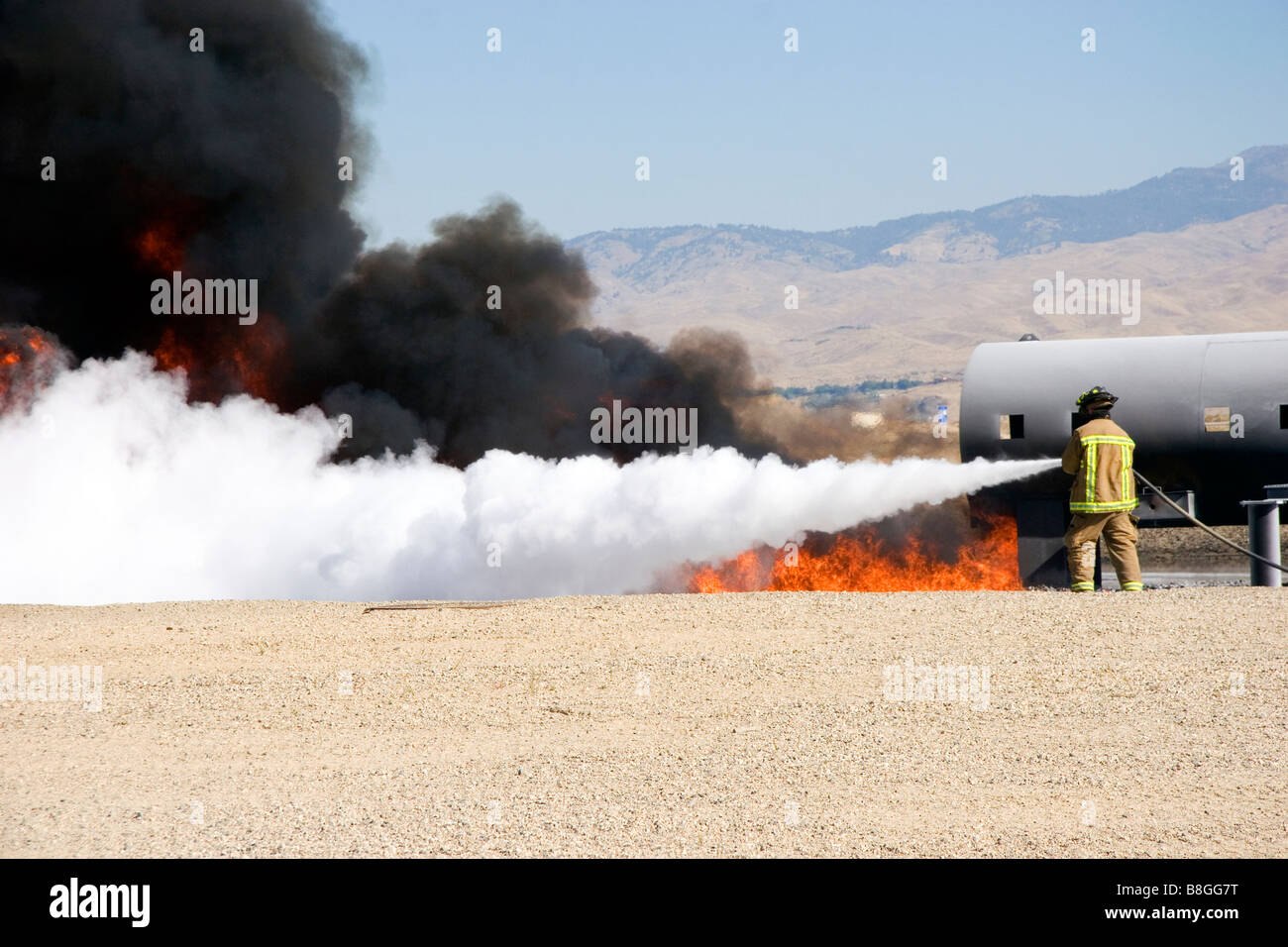 Firefighter using fire retardant foam to put out a jet fuel fire at an