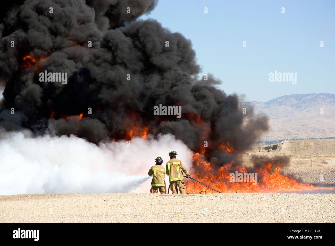 Firefighters using fire retardant foam to put out a jet fuel fire at an airport training