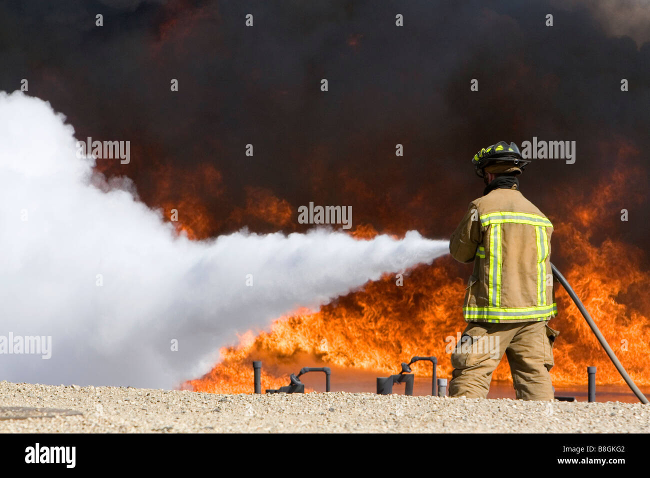 Firefighter using fire retardant foam to put out a jet fuel fire at an airport training facility in Boise Idaho USA Stock Photo