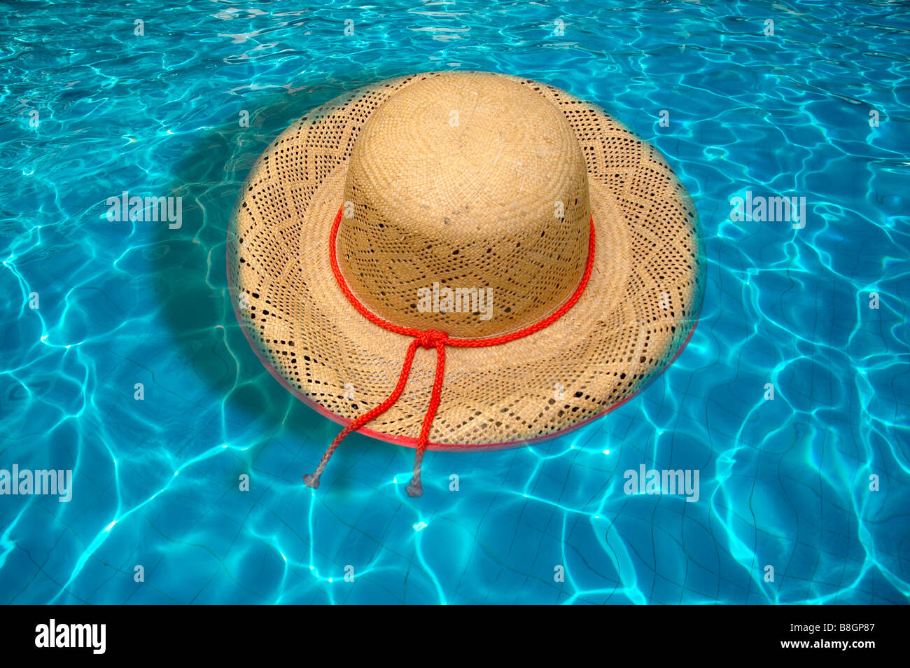 A summer straw hat floating on water of a swimming pool. Stock Photo