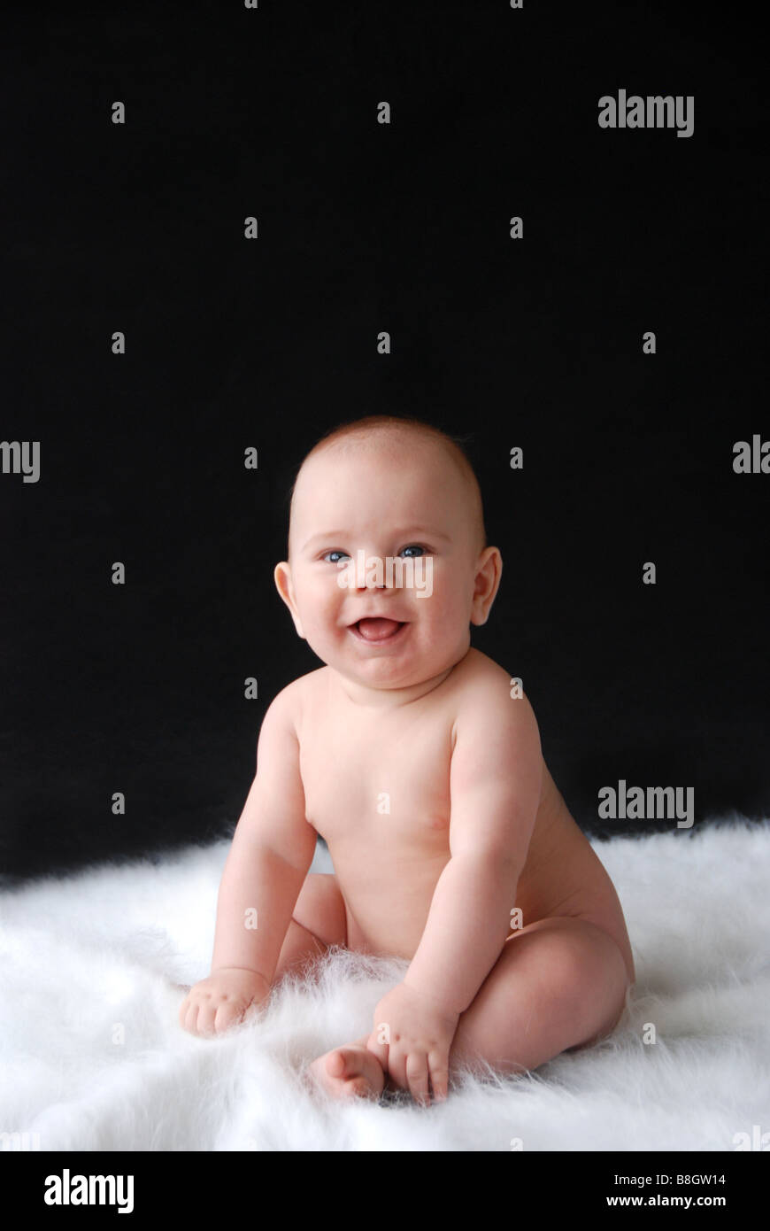 Naked baby sitting up with big smile Stock Photo