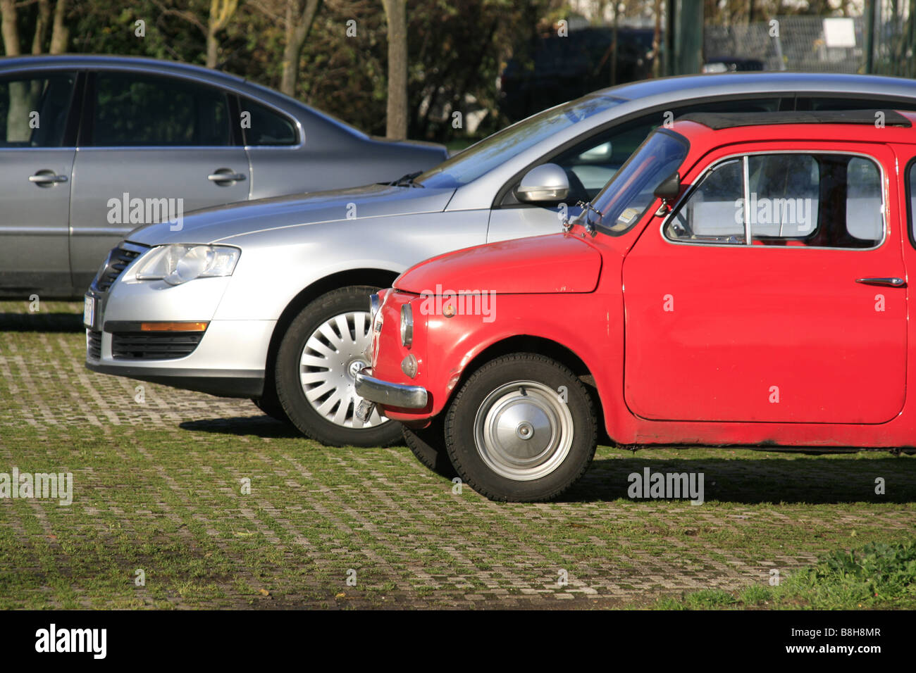 one old red fiat 500 car and other luxury cars parked in countryside ...