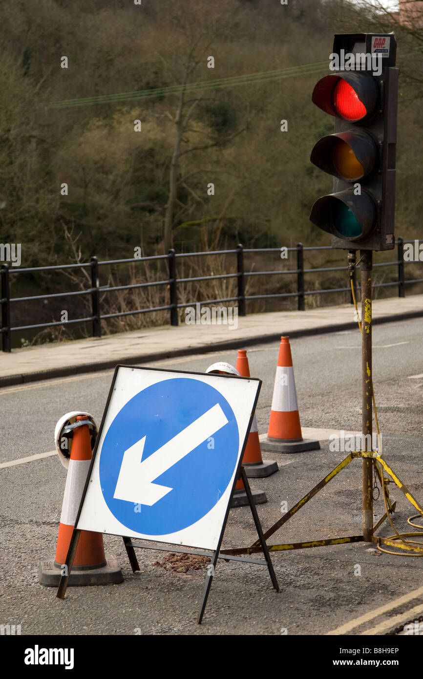 Temporary traffic lights with a keep left sign and numerous traffic cones at the site of roadworks Stock Photo
