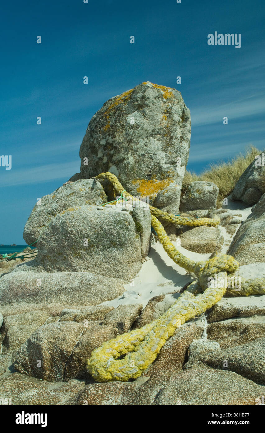 Granite Rock on St Martins Isles of Scilly used as mooring post with mooring rope around it on the beach Stock Photo