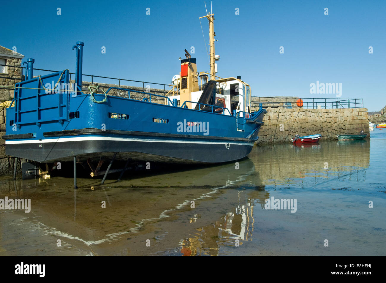 Large Blue boat tied up alongside harbour wall on St Marys Scilly Isles Scillies Stock Photo