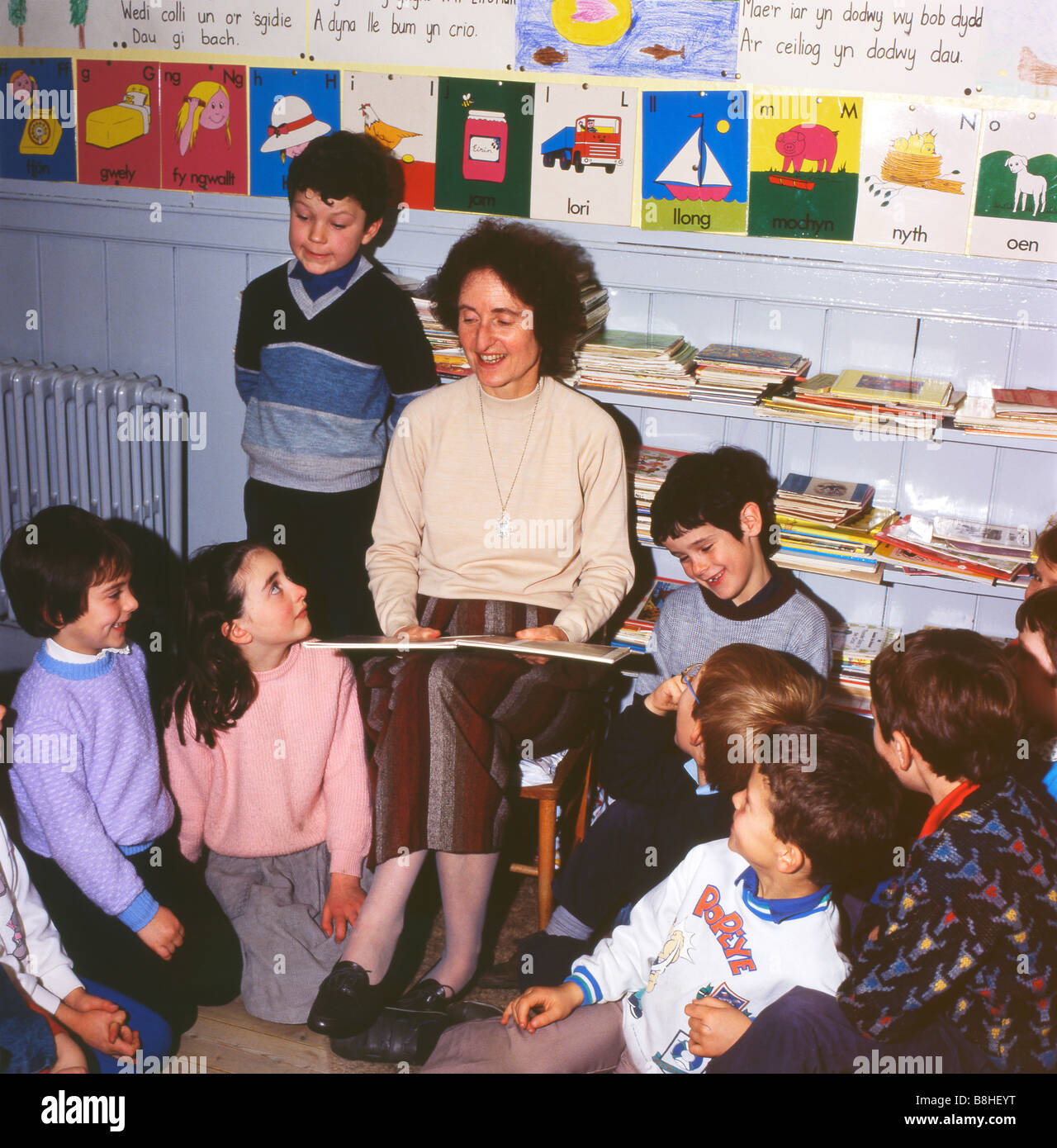 Teacher reading a book to pupils inside a classroom at rural village school in Ffarmers Carmarthenshire Dyfed Wales UK 1980s education  KATHY DEWITT Stock Photo