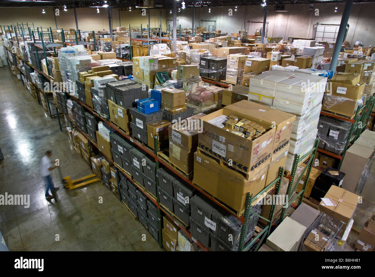Warehouse full of inventory seen from above with worker using forklift. Stock Photo
