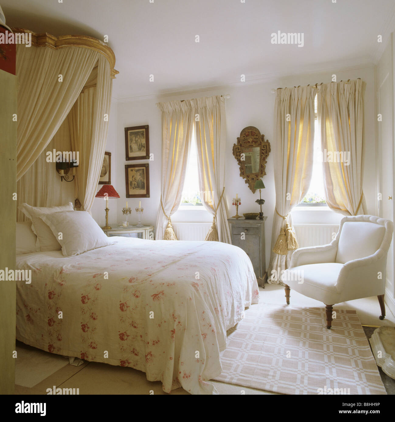 Traditional bedroom with a feminine feel, corona and muslin bedhangings and a gilded Italian 18th century mirror Stock Photo
