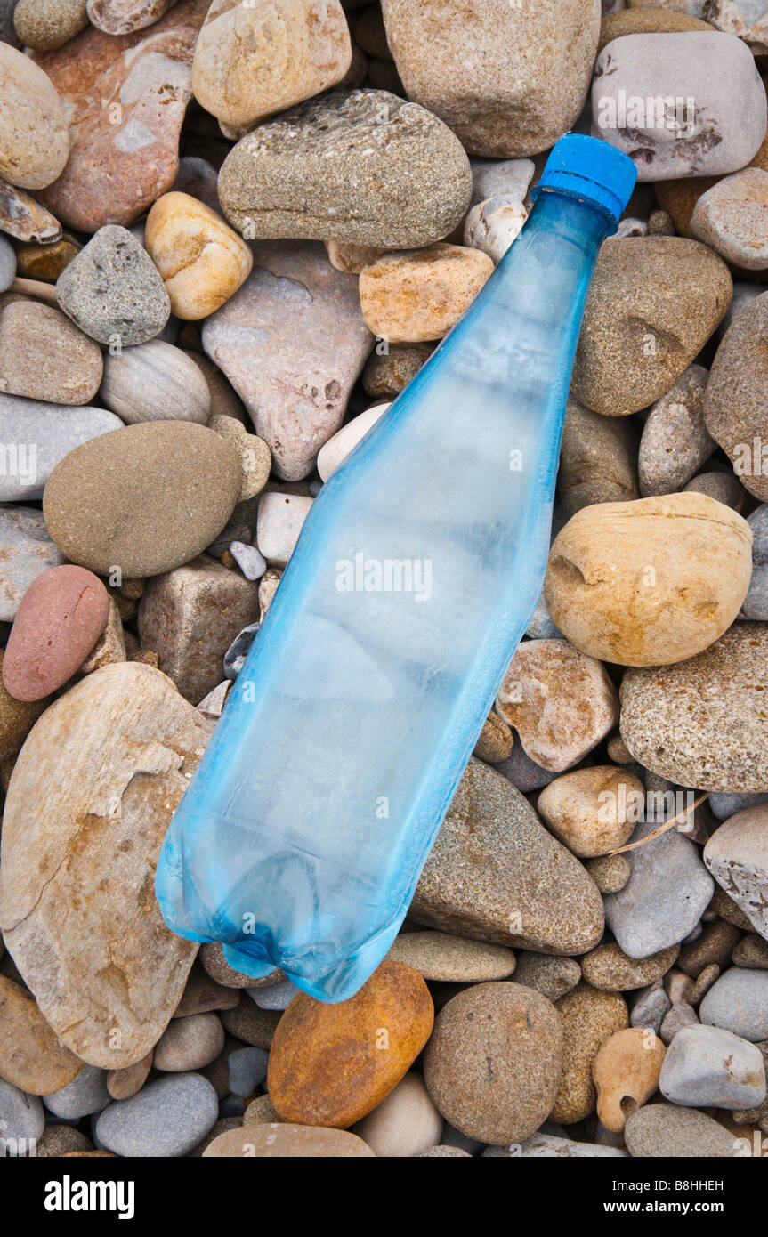 An old blue water bottle washed up on a pebble beach Stock Photo