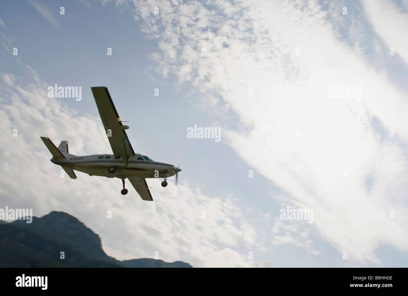 Cessna Caravan (C208) is doing a flyby close to the ground with mountains in the background as reverence. Stock Photo